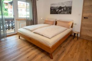 1 dormitorio con 1 cama grande y suelo de madera en Ferienwohnung Bergspitz, en Pfronten