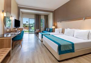 a hotel room with two beds and a desk at Kaya Side in Side