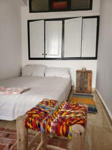Un dormitorio con una cama con una manta de colores. en Vanila Taghazout, en Taghazout