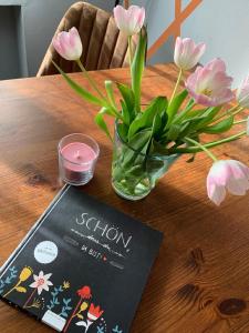a vase of pink flowers on a table with a book at Appartement in Pommern mit Garten und Grill in Pommern