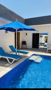 a swimming pool with two chairs and an umbrella at Dar Adam in Djerba