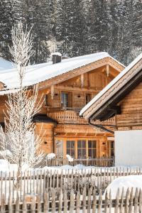 a log cabin in the snow with a fence at Birnbaum Chalet Kreuzkogel mit Naturbadesee und eingezäunten Garten in Grossarl