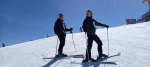 two men standing on a snow covered slope on skis at Birnbaum Chalet Kreuzkogel mit Naturbadesee und eingezäunten Garten in Grossarl