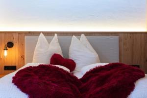 a bed with white pillows and red blankets at Birnbaum Chalet Kreuzkogel mit Naturbadesee und eingezäunten Garten in Grossarl