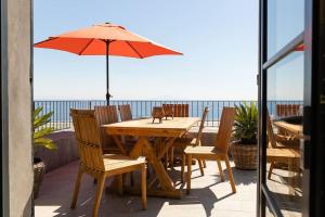 una mesa de madera y sillas con sombrilla en el patio en Belle villa vue mer- Erbalunga à 2 pas de la plage, en Brando