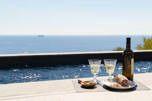 Belle villa vue mer- Erbalunga à 2 pas de la plage في Brando: طاولة مع زجاجة من النبيذ وكأسين