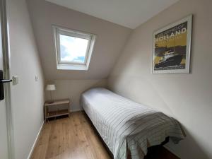 una piccola camera con letto e finestra di De Bakkerij a Baaiduinen