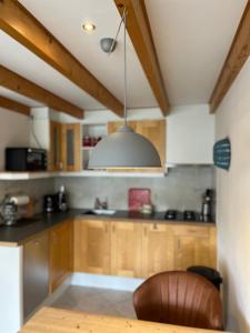 a kitchen with wooden cabinets and a pendant light at De Bakkerij in Baaiduinen