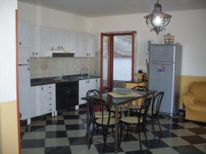 Una cocina con mesa y sillas y un refrigerador. en Villa del Capo, en Capo Vaticano
