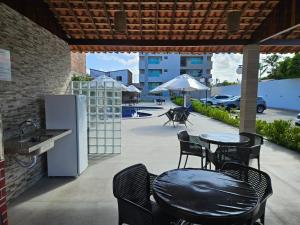 a patio with a table and chairs and an umbrella at Apartamento Encantador - MAKAMBIRA RESIDENCE in Porto De Galinhas