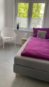 a bedroom with a purple bed and a chair at Villa Mariensiel 1OG li in Sande