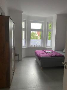 sypialnia z purpurowym łóżkiem i 2 oknami w obiekcie Villa Mariensiel 1OG li w mieście Sande