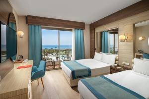 a hotel room with two beds and a balcony at Kaya Side in Side
