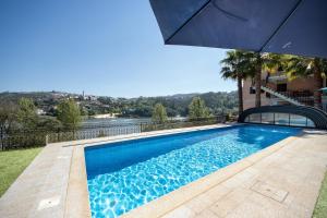 a swimming pool with an umbrella next to a house at Porto Douro - appartement 1 in Crestuma