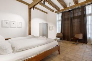 a bedroom with a large white bed and some windows at Loft Im Künstlerhaus in Riegel am Kaiserstuhl