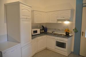 a white kitchen with white cabinets and a microwave at 1 Schwerin in Borkow