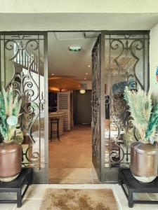 une porte ouverte avec deux plantes en pot dans un couloir dans l'établissement Hostellerie Le Paradou, à Lourmarin