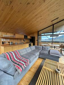 a large gray couch in a room with a wooden ceiling at AvA Refugios Malalcahuello in Malalcahuello