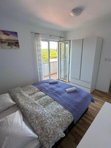 ein Schlafzimmer mit einem Bett und einem großen Fenster in der Unterkunft Family Deluxe Apartment Mirjana in Kampor