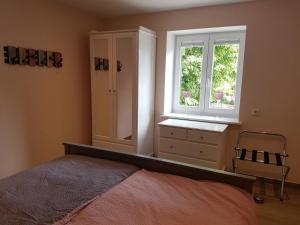 ein Schlafzimmer mit einem Bett, einer Kommode und einem Fenster in der Unterkunft Haferspieker in Mittelangeln