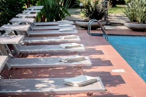 a row of lounge chairs next to a swimming pool at Hotel Bellevue in Gardone Riviera