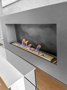 een open haard met vier vlammen in een grijze oven bij Le Lumineux - Proche centre-ville et Atlantis in Saint-Herblain