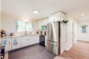 a kitchen with white cabinets and a stainless steel refrigerator at Shell House in Waianae