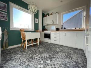 a kitchen with green walls and a table and a chair at Large, central and quiet apartment. in Stavanger