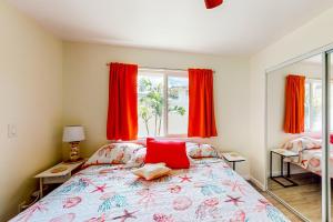 a bedroom with a bed and a window with red curtains at Shell House in Waianae