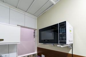 a microwave hanging on a wall in a kitchen at 38 LOFT DUPLO · LOFT perto da São PauloExpo /Aeroporto Congonhas in São Paulo