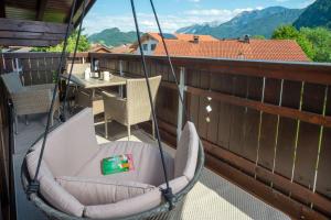 Un columpio en un balcón con una mesa y montañas. en Ferienwohnung Bergnasennen, en Pfronten