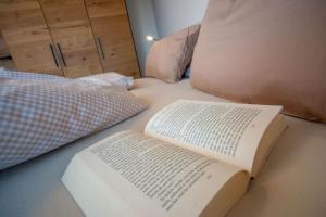 een boek op een bed naast een kussen bij Ferienwohnung Bergnasennen in Pfronten