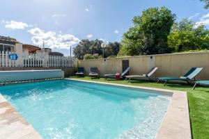 a swimming pool in a yard with chairs and a fence at La Petite Maison in Bédoin