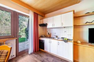eine Küche mit weißen Schränken und einem großen Fenster in der Unterkunft Alpenhof Lodge Almrose in Saltaus