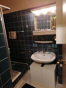 La salle de bains est pourvue de carrelage noir, d'un lavabo et d'un miroir. dans l'établissement Wohnung in Hahnenklee mit Garten, à Goslar