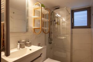 W łazience znajduje się umywalka i przeszklony prysznic. w obiekcie Carmen's cozy&luxury apartment! w Atenach