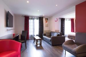 a living room with a couch and a bed at Hôtel Restaurant Les Coquelicots, The Originals Relais (Inter-Hotel) in Saint-Pardoux-lʼOrtigier