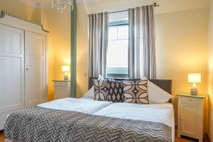Un dormitorio con una cama con almohadas y una ventana. en FeWo Lieselotte, en Borkum