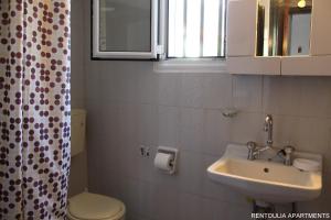 a bathroom with a sink and a toilet at Rentoulia Apartments in Poulithra