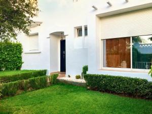a white house with a black door and green grass at 4 bedrooms villa at Dar Bouazza Tamaris 200 m away from the beach with private pool and enclosed garden in Dar Bouazza