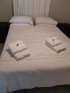 - un lit blanc avec des serviettes dans l'établissement Oak Terrace 39, à Hermanus