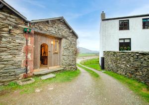 an old stone building next to a stone wall at Dog Crag Cabin in Silecroft