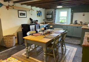 uma cozinha com uma mesa de madeira e cadeiras em Moorland View em Cotterdale