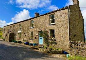 an old stone house with a blue door at Moorland View in Cotterdale