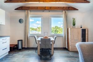 a dining room with a table and two windows at Nr 5 Bernuthsfeld mit Loggia in Aurich