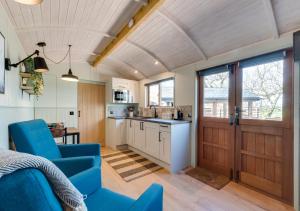 a kitchen and living room with blue chairs and a door at Esk Escape in Longtown