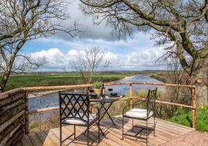 a table and chairs on a wooden deck next to a river at Esk Escape in Longtown