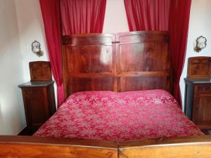 una camera con letto in legno e tende rosse di La Casa Nel Bosco a Beverino