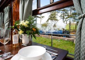a table with a bowl of flowers and a train through a window at Esk Pullman Carriage in Ravenglass