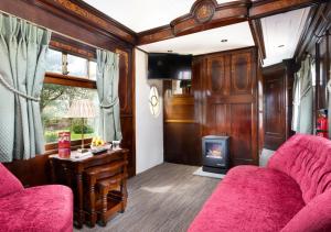 a living room with a red couch and a stove at Esk Pullman Carriage in Ravenglass
